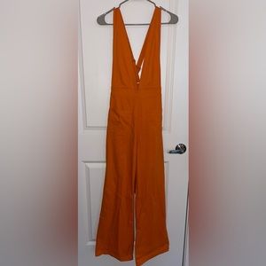Orange V neck jumpsuit, adjustable straps, flared pant legs, size M